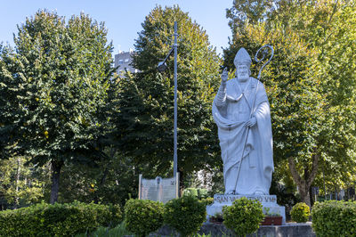 Statue by trees against sky