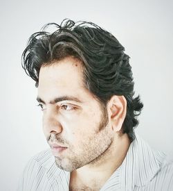 Portrait of young man looking away against white background