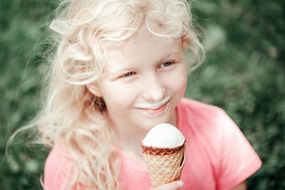 Girl eating licking ice cream from waffle cone. child eating sweet cold summer food outdoor