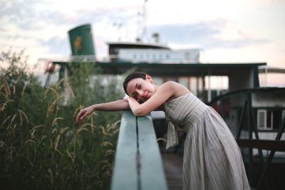 Portrait of young woman standing by railing