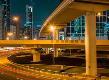 Light trails by illuminated bridge in city at night