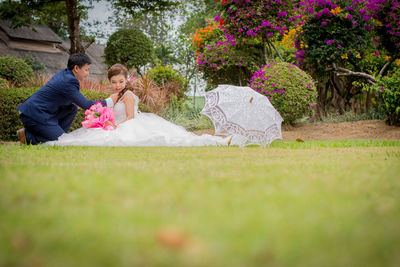 Newlywed couple romancing on grassy field at public park