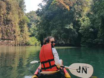 Man sitting in lake against trees