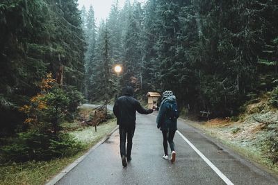 Rear view of women walking on road in forest