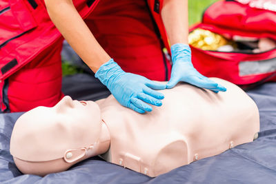 Midsection of paramedic practicing cpr on dummy