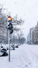 Snow covered street amidst buildings in city