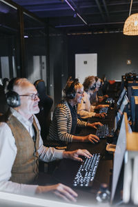 Senior male and female friends playing video game on computers in gaming lounge