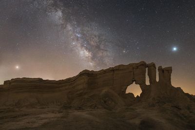 Milky way above rockcliffs .
 mars at left, jupiter at right  and saturn at the middle of milky way.