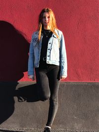 Portrait of young woman standing against wall