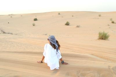 Rear view of woman walking in desert