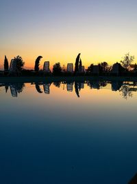 Silhouette swimming pool by lake against sky during sunset