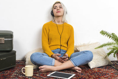 Portrait of young woman using laptop while sitting on sofa against white background