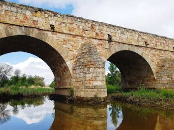 Arch bridge over river against sky