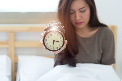 Portrait of young woman holding clock