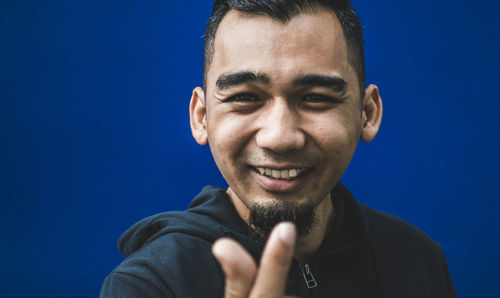 Portrait of young man against blue background