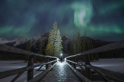 Footbridge over water against sky at night