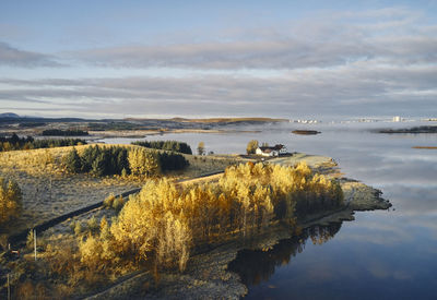 Autumn trees and houses on shore of lake in evening