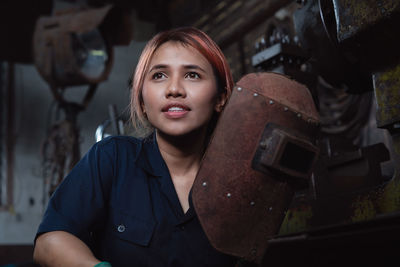 Young woman looking away while holding work helmet