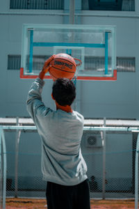 Rear view of man standing against basketball hoop