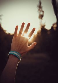 Optical illusion of cropped hand gesturing against sky during sunset