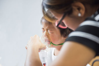 Close-up of mother holding nebulizer for sick daughter at home