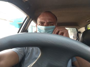 Indian man wearing surgical mask and driving