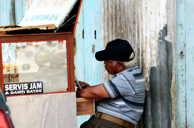 Side view of man sitting by door