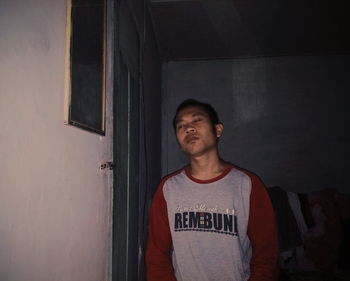 Portrait of young man standing against wall