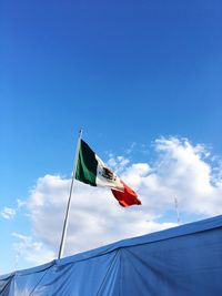 Low angle view of flag against blue sky