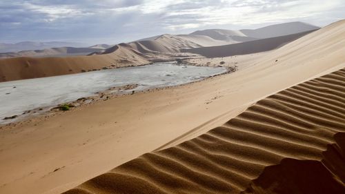 Scenic view of desert against cloudy sky