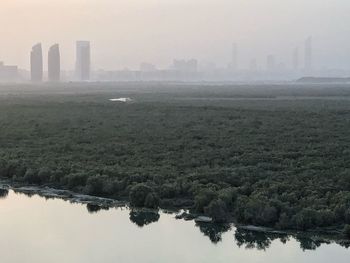 Scenic view of river by buildings in city against sky