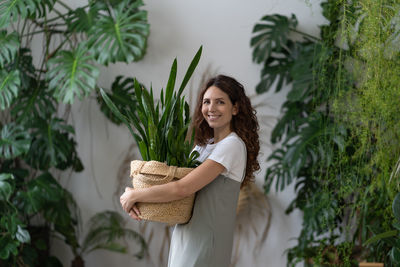 Love for plants. happy woman hold pot with sansevieria houseplant smiling in indoor garden at home
