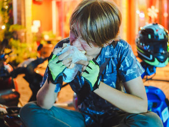 Young man eating sandwich while sitting on motor scooter outdoors