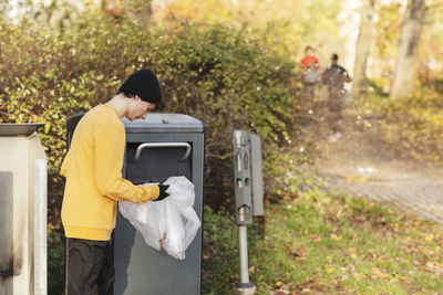 Male volunteer throwing plastic waste in garbage can