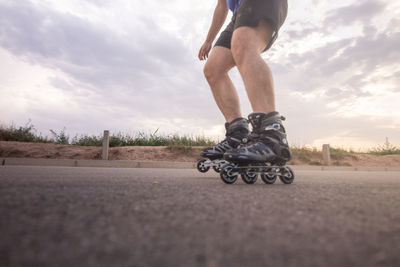 Low section of man rollerskating on road