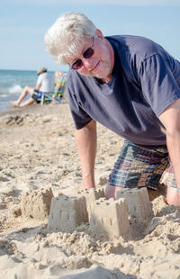 Senior man is building sand castles during retirement on the beach