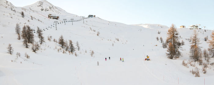 Panoramic view of people skiing on snowcapped mountain against sky