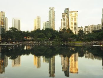 Reflection of buildings in lake against sky in city