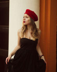 Woman looking away while standing against wall