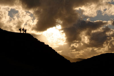 Three people on silhouette rocks