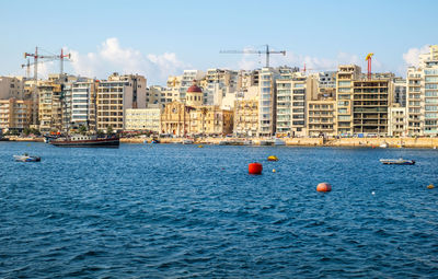 Boats in sea against buildings in city