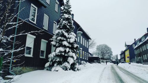 Snow covered street amidst buildings against sky