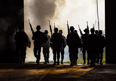 Army soldier with rifle walking against sky