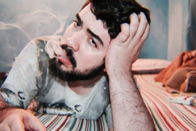 Portrait of young man sitting on bed at home