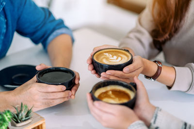 Midsection of woman holding coffee cup on table