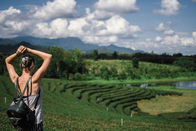 Midsection of woman standing on field against sky