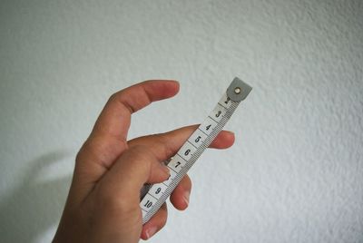 Close-up of human hand against white wall