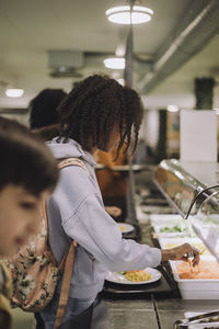 Side view of schoolgirl during lunch break in cafeteria