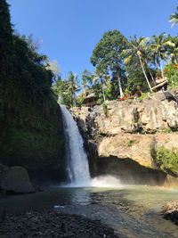 Scenic view of waterfall in forest against sky