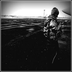 Rear view of man walking at beach against clear sky